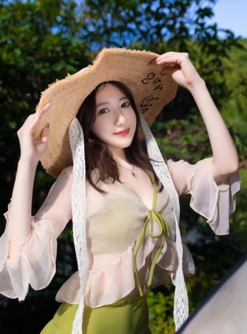 戴草帽的年轻女子在绿树下，清新自然。