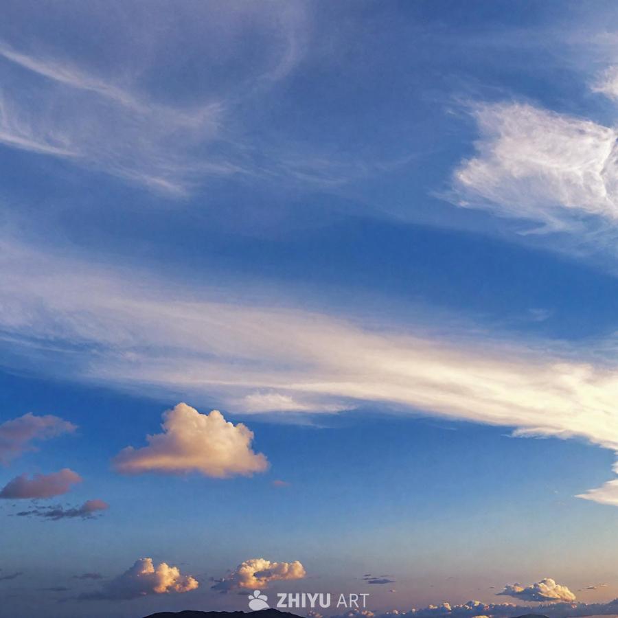 蓝色的天空中有各种形状的云朵，一些云朵看起来离前景
