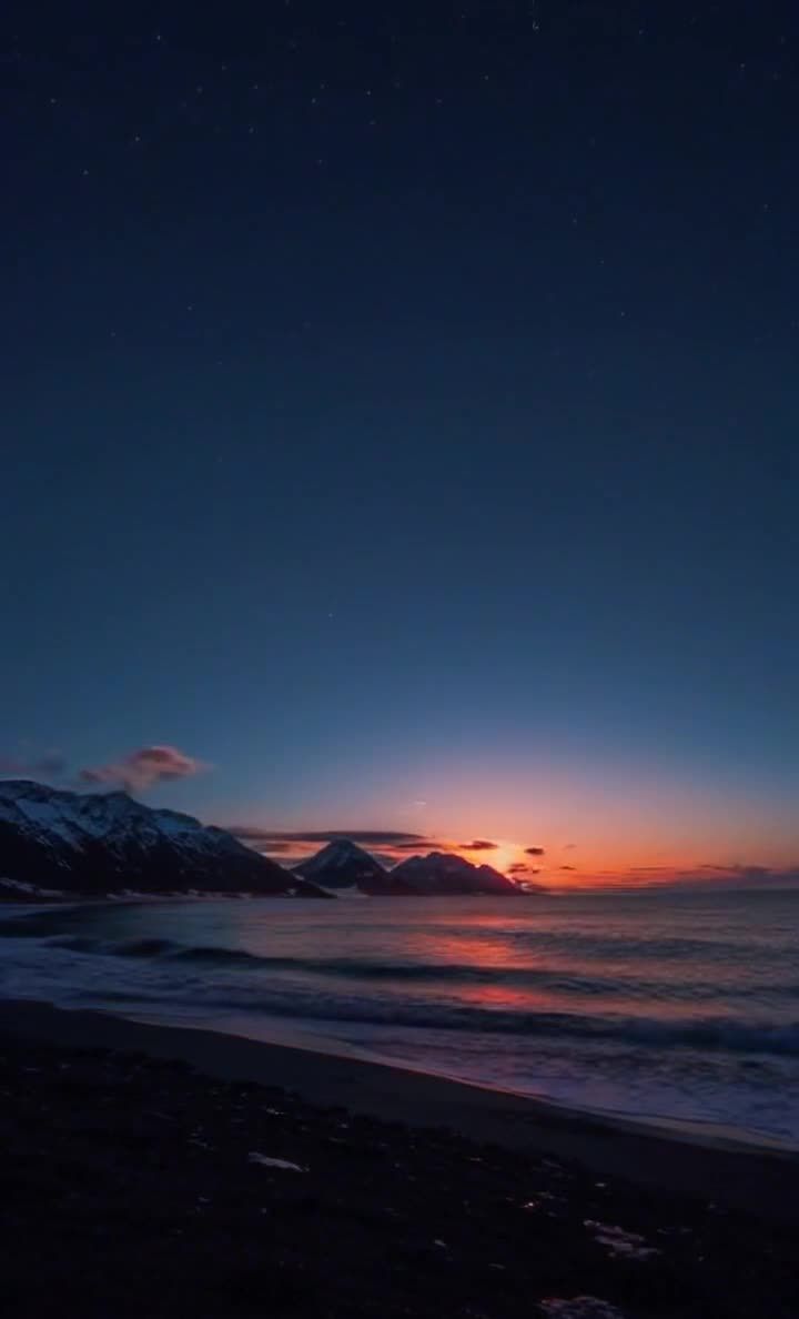 夜幕下的海滩和山脉，天空渐变色彩。