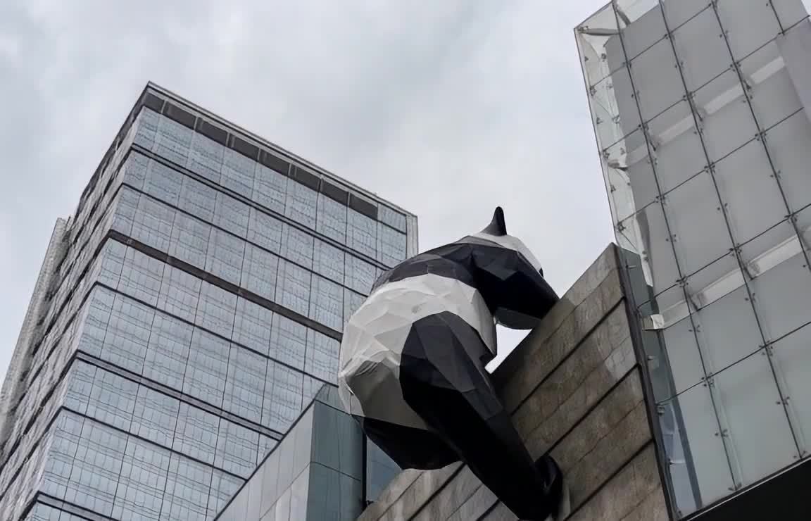 黑白熊猫雕塑攀爬现代建筑外墙
