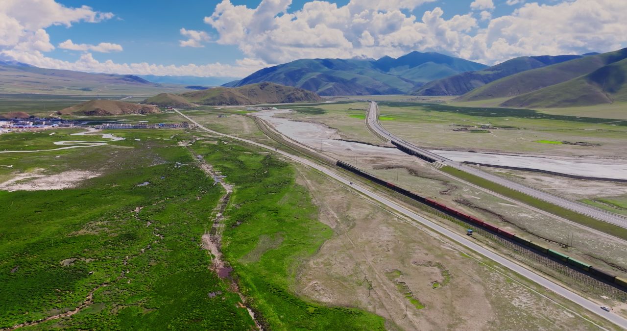 西藏那曲青藏高原雪山草原之间青藏铁路行驶的列车大气航拍