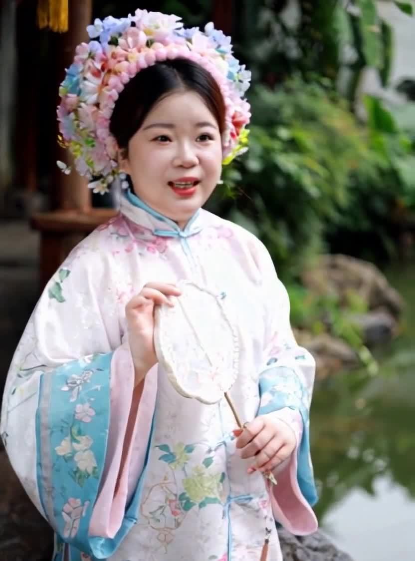 一位女性身穿古装，头上戴着由多种颜色鲜花组成的头饰