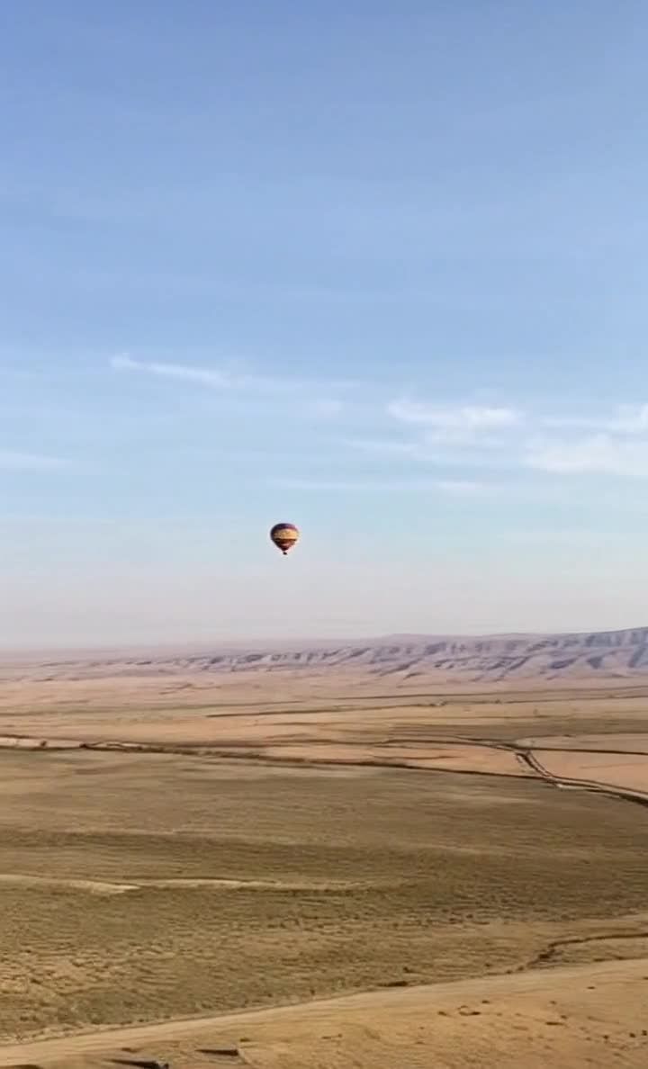 荒漠上空的彩色热气球，天空背景有山脉。