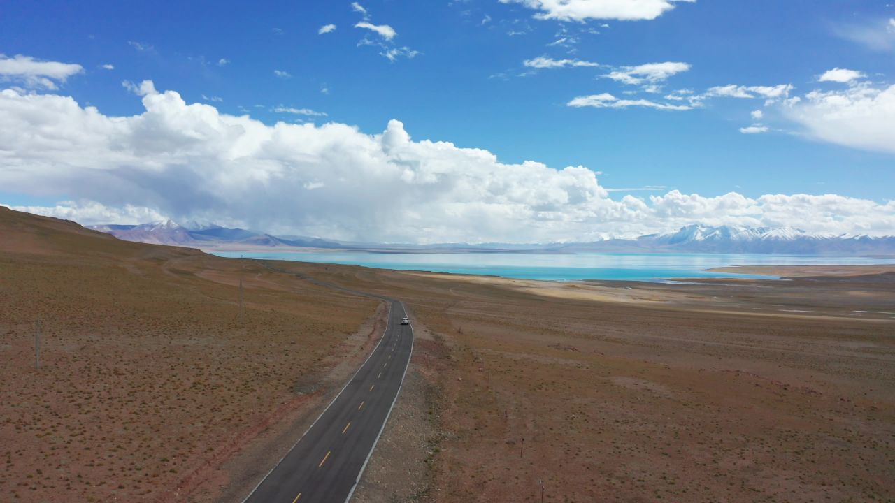 航拍汽车行驶在西藏当惹雍错湖边的公路上