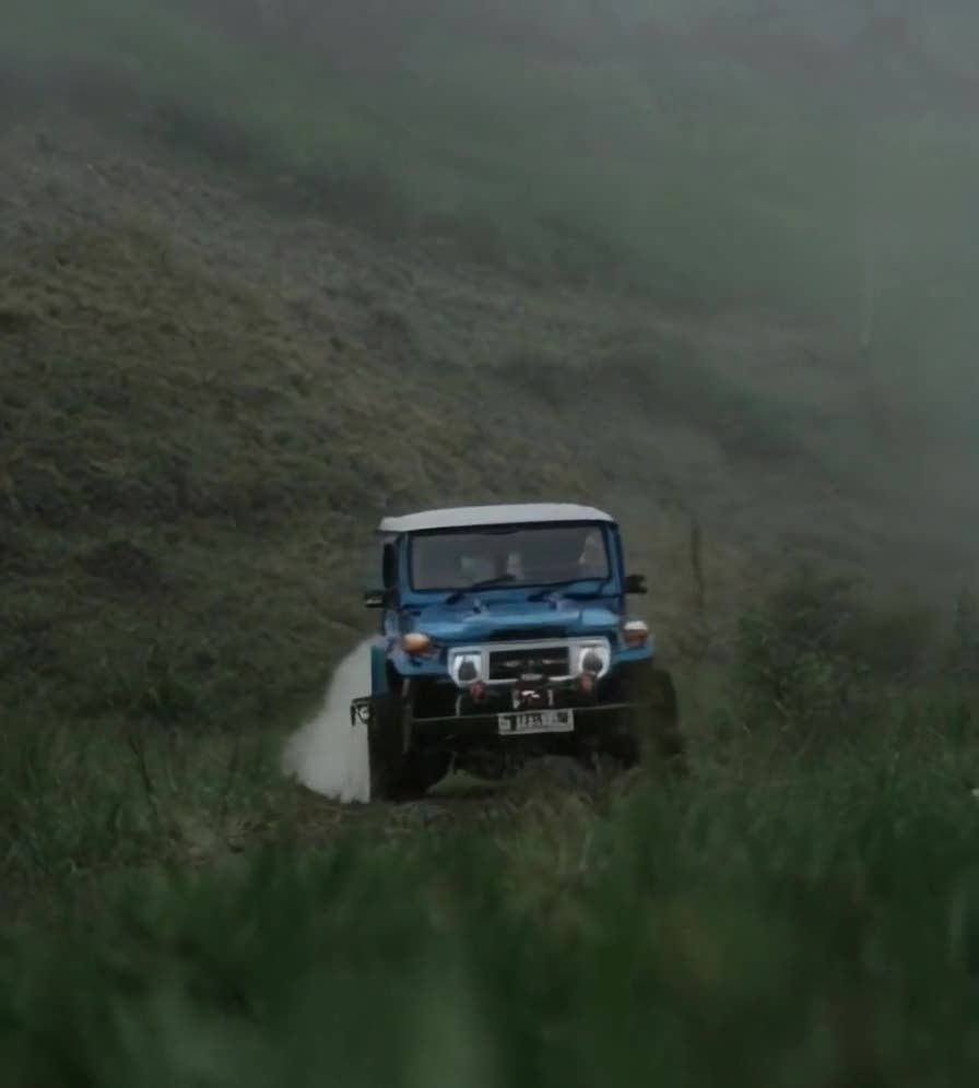 雾气山坡上的蓝色越野车