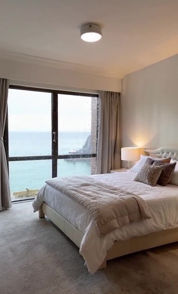 雨天海景卧室：舒适床铺，光线柔和，窗外雨水模糊海景