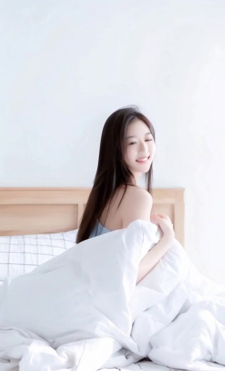 长发女子，肩部微露，格纹床单，白色被子，木制床头