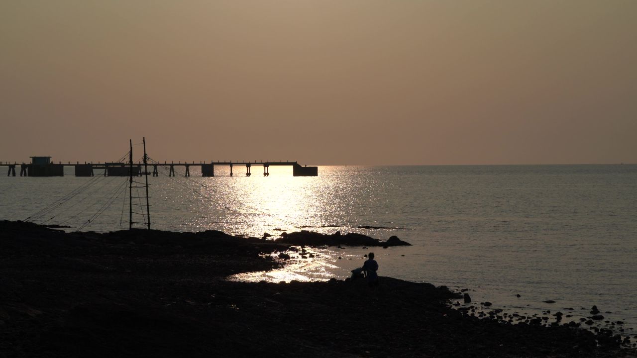 北海冠头岭夕阳海面小渔船驶过桥底