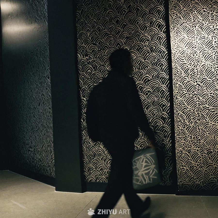 昏暗的房间里，一个人背着黑色背包走动。墙壁上装饰着
