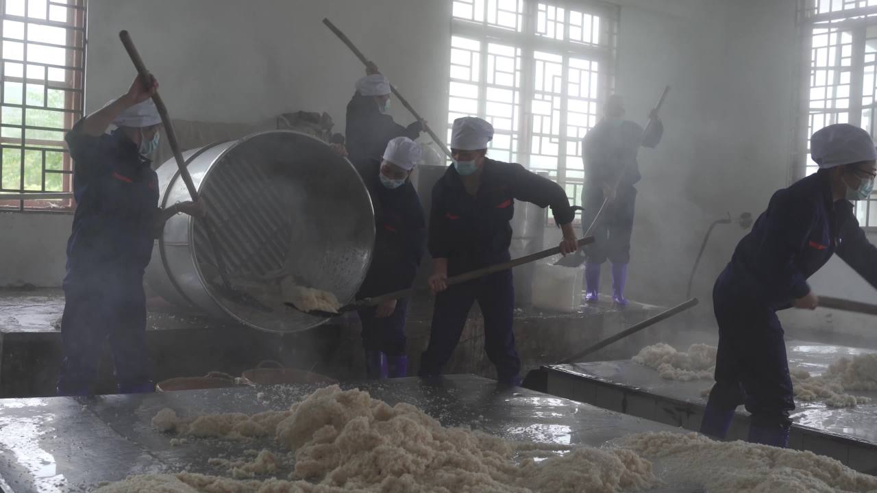 工厂工人们在蒸汽中协作搅拌
