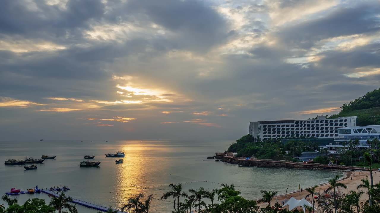  海边酒店与海面船只晚霞景观