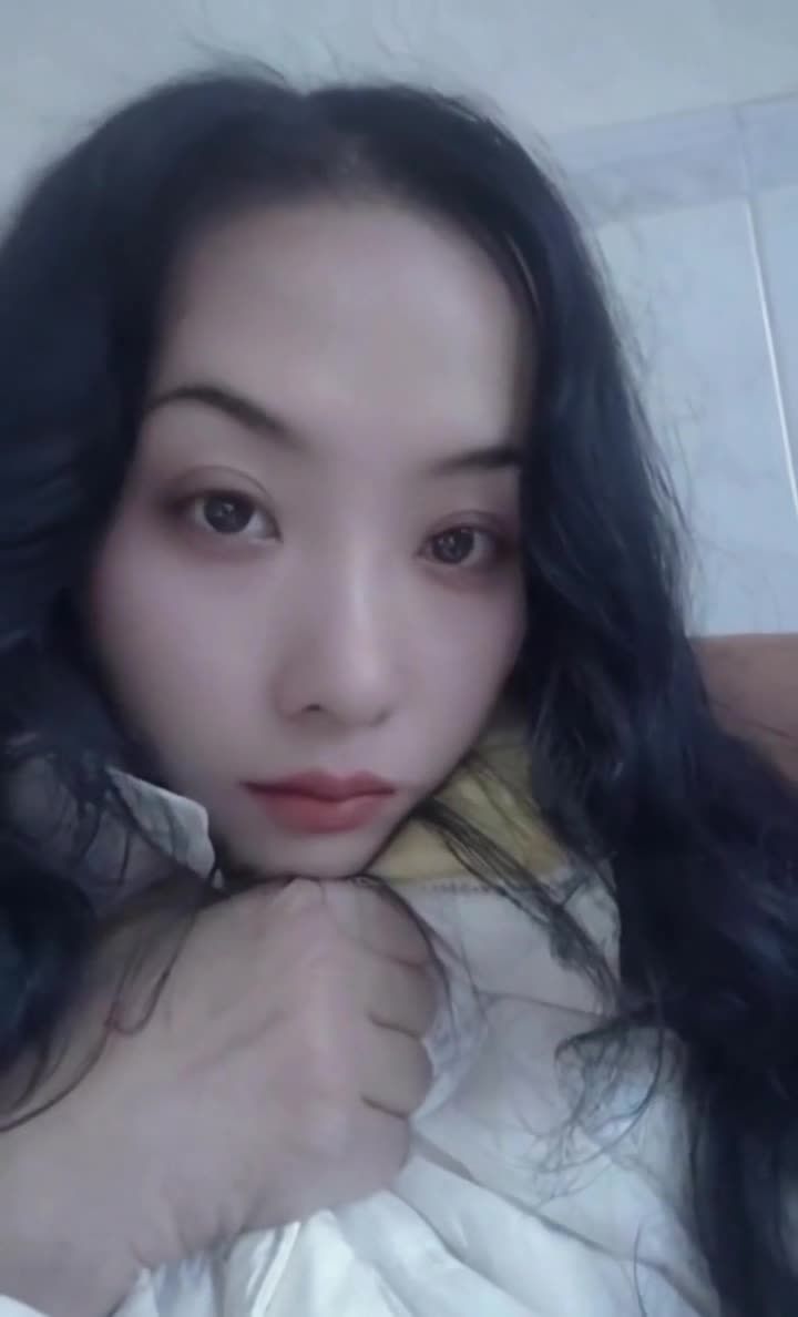 一位留着黑色长发的女性，她面部朝向镜头，眼神注视着