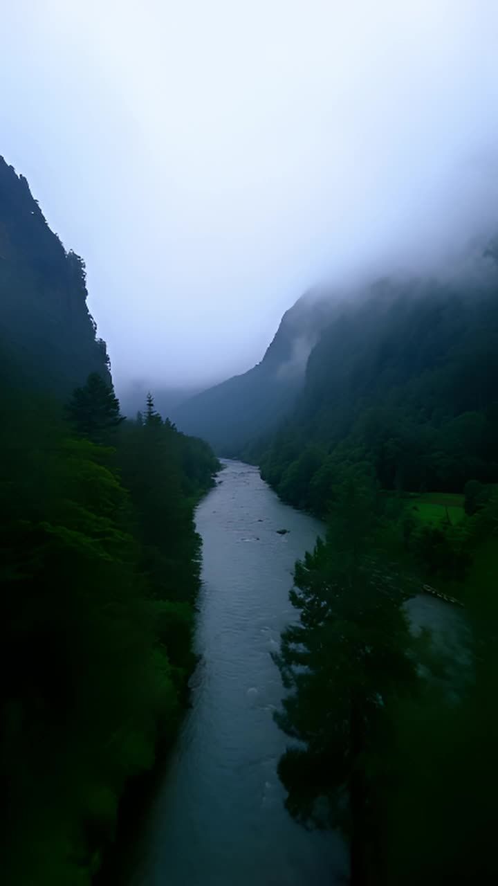 山谷被高耸的山脉环绕，山顶在浓雾中隐约可见。山谷中
