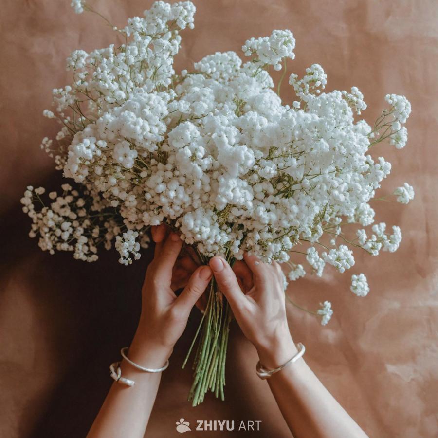 一个人手中拿着一束白色鲜花，可能是满天星。鲜花以视