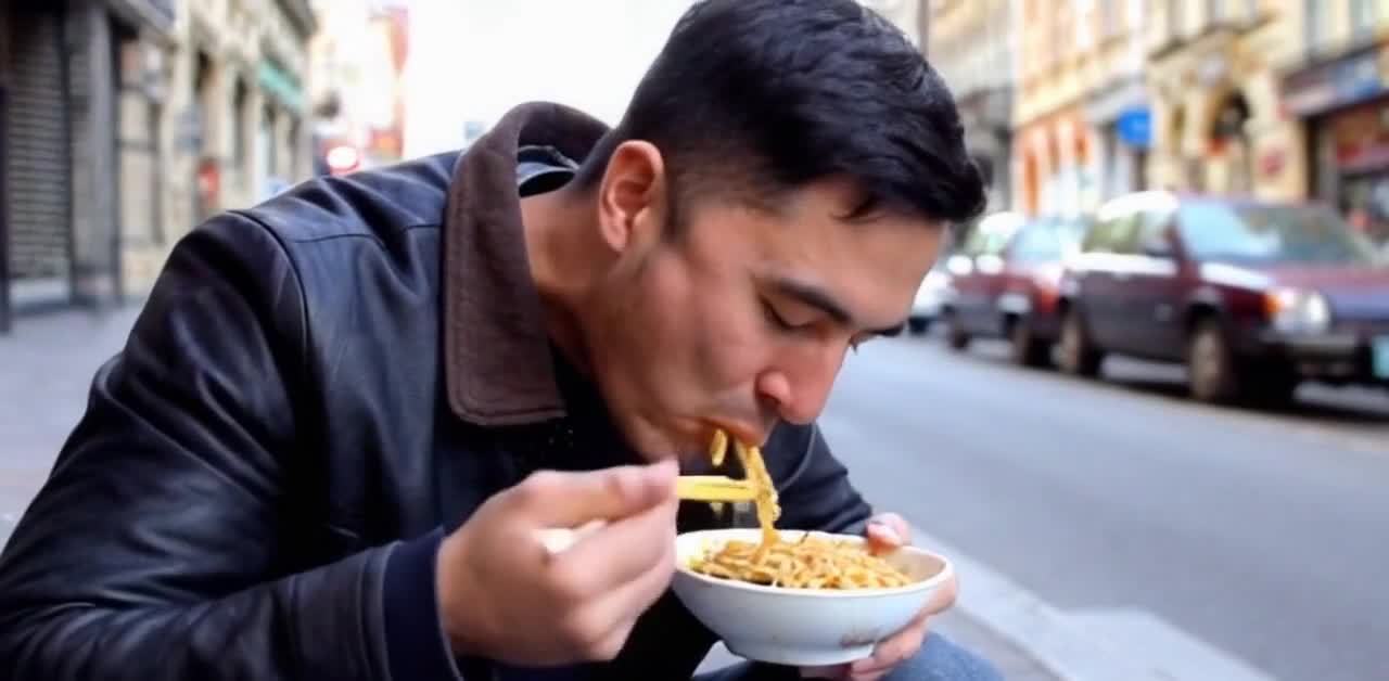 街边男子吃面：一碗热腾腾的面条，美味可口。
