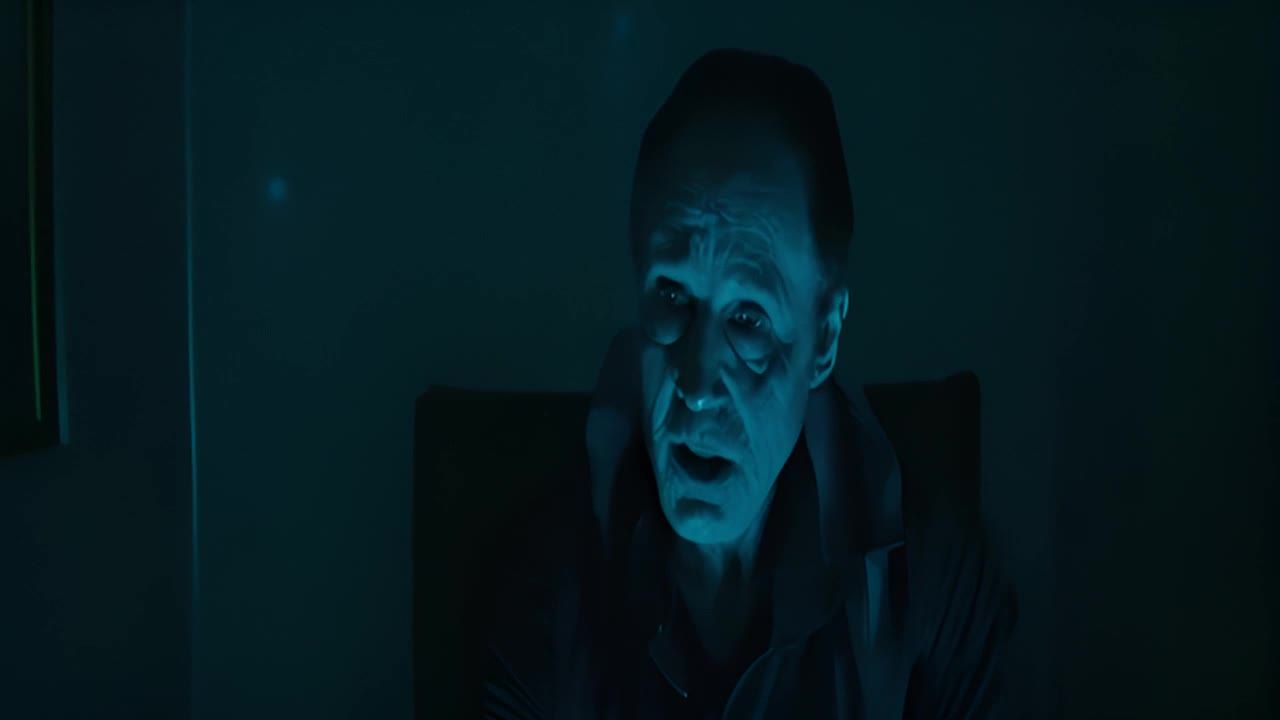 在昏暗的房间里，一个人坐在椅子上。房间光线很暗，只