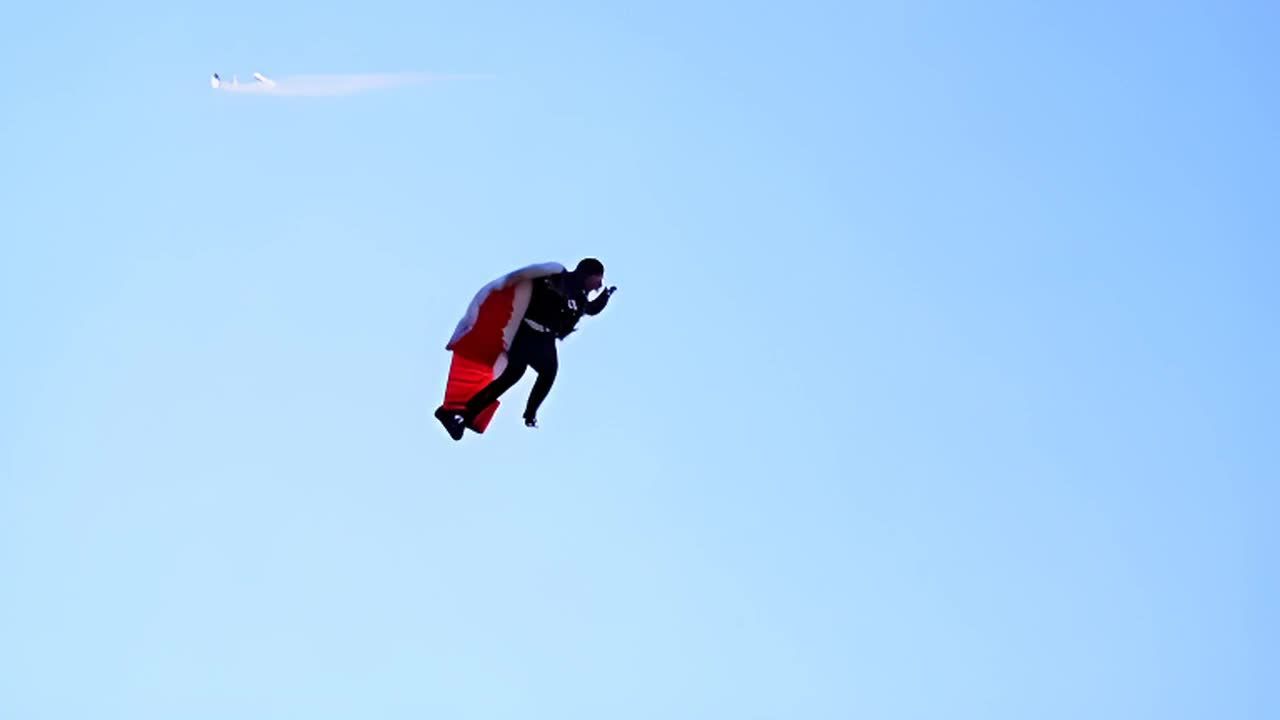 一个穿着翼装的人从空中落下，他的身体在广阔的蓝色背