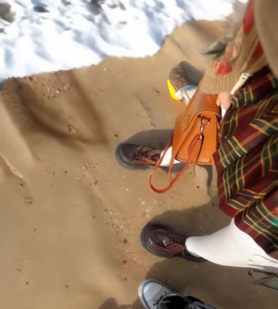 沙滩上的两人与棕色皮包和退潮的海水