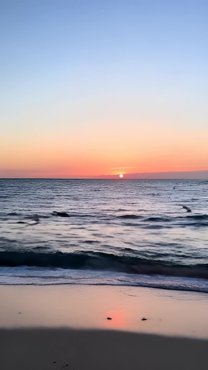 日落时宁静的海滩。相机从低角度拍摄，展现广阔的天空