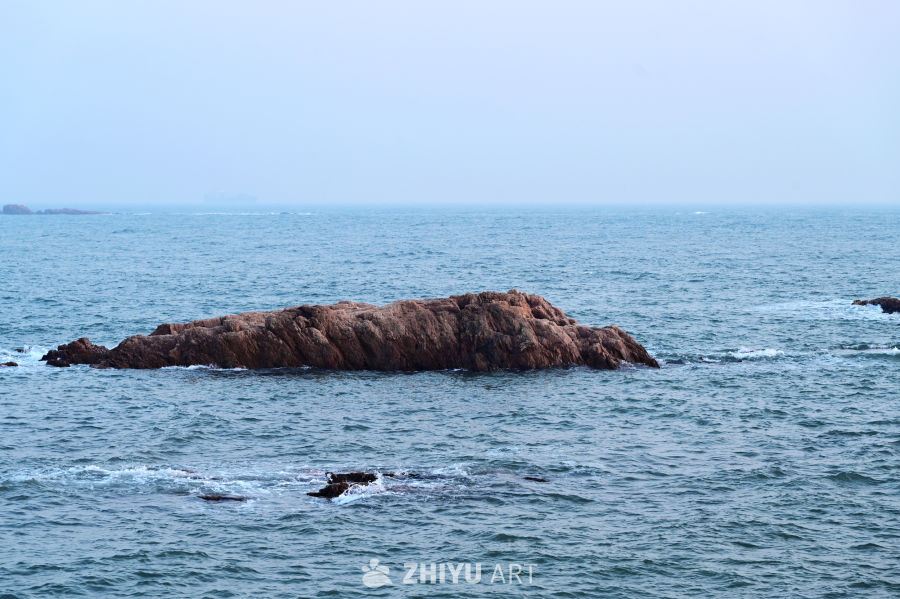 晴朗的天空，青岛蔚蓝海面上的礁石