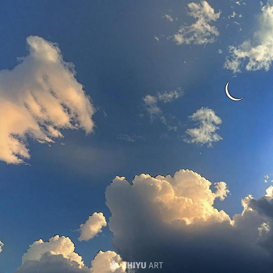 天空是蔚蓝色的，漂浮着许多云朵，月亮位于天空的左侧