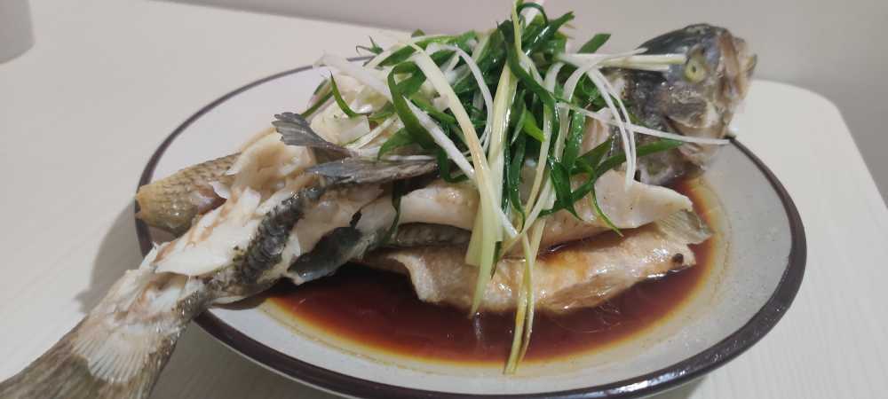 白色盘子里的清蒸鱼晚餐