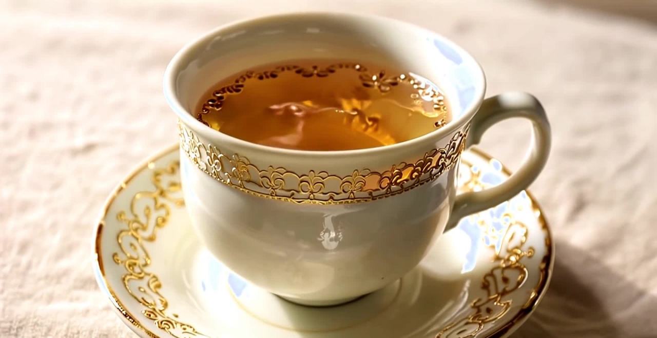 金色花纹装饰的茶杯与茶托及杯中清澈液体