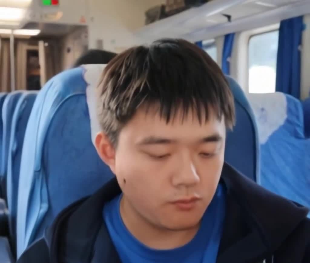 闭眼男子在火车上，蓝色座椅和窗帘。