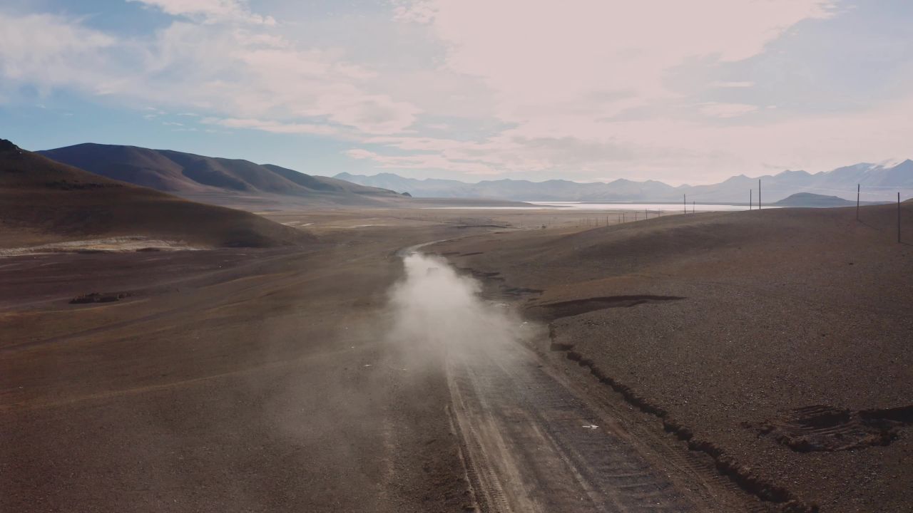 航拍越野车行驶在西藏阿里无人区的荒漠中，车后扬起尘烟
