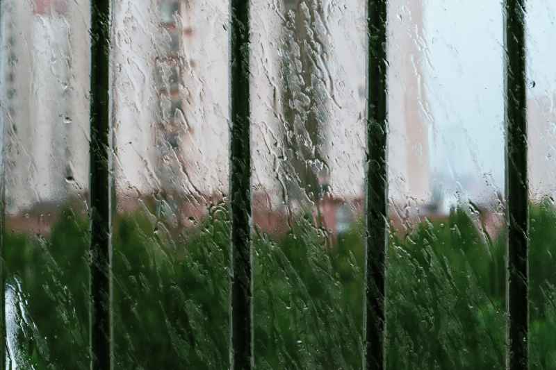 下雨天玻璃窗上的水珠和窗外栏杆的牢笼