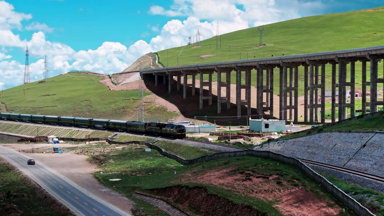 西藏那曲青藏高原雪山草原之间青藏铁路行驶的列车大气航拍