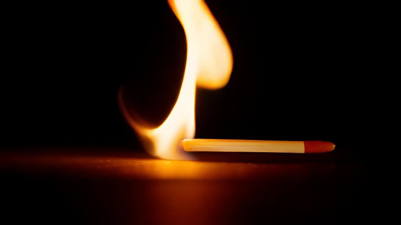 一根火柴从画面外滚入，点燃并开始燃烧。火焰迅速蔓延