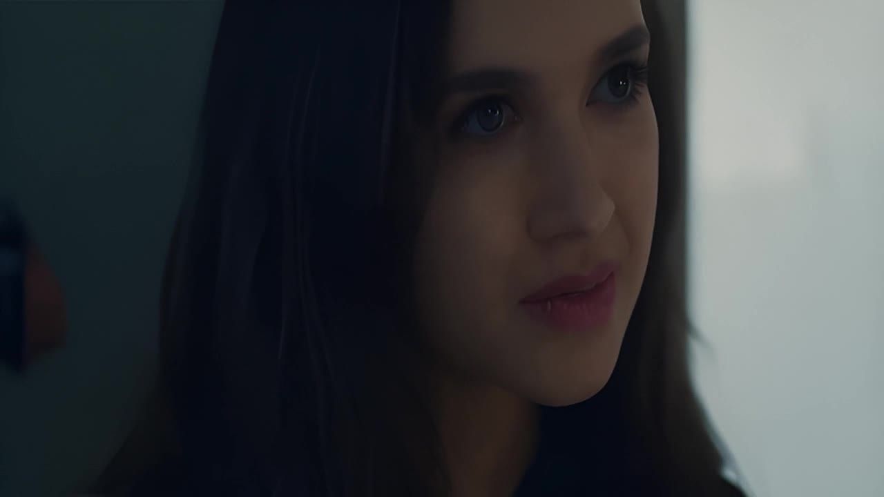 一个有着深色长发的女子，她的眼睛看着画面外，嘴唇微