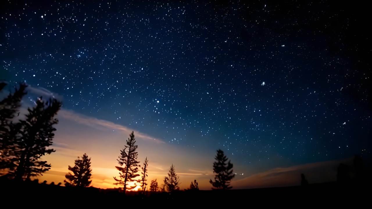 夜空中，布满了星星，天空呈现深蓝色，地平线上有橙色