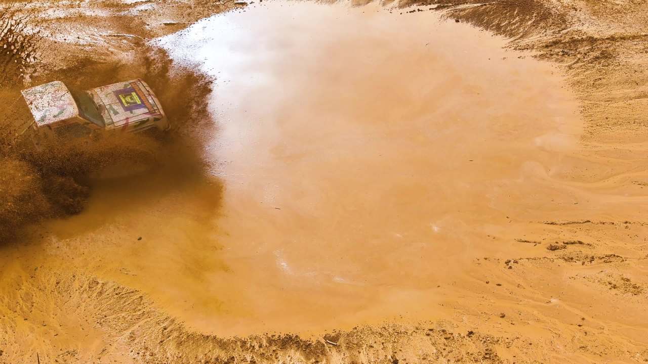 改装汽车经过水坑路段溅起泥水航拍