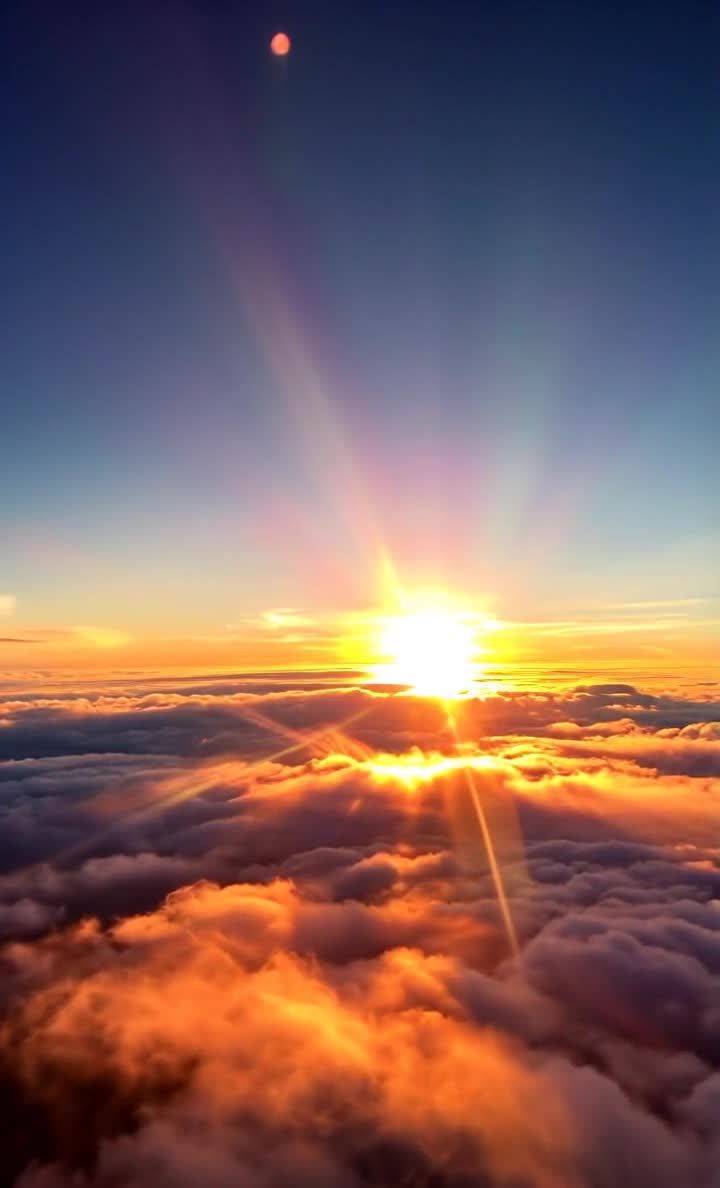 从高空俯视，一片云海，阳光穿透云层，云层呈现出橙色