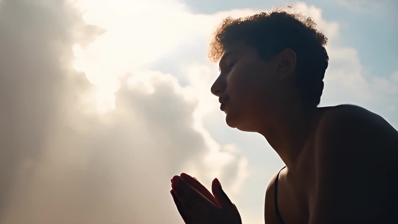 一个人跪在一个宁静而超凡的环境中祈祷。阳光透过云层