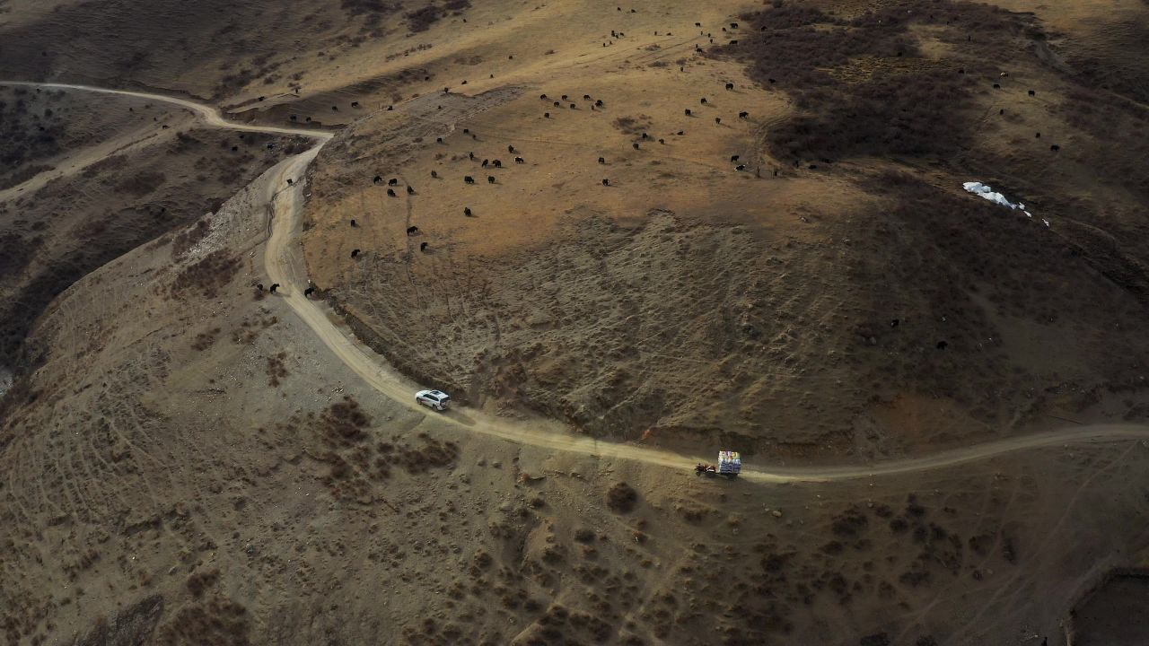 越野车行驶在高原草甸半山腰的土路上