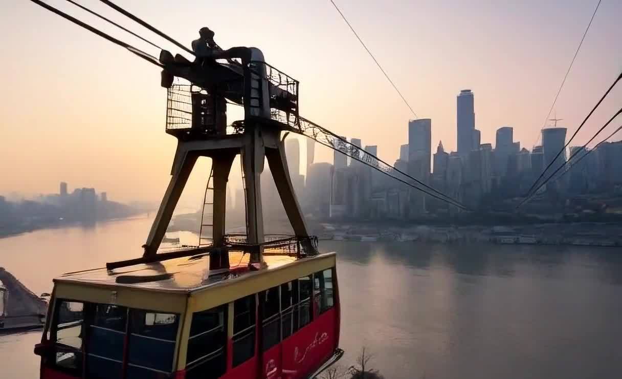 一辆红色缆车悬挂在空中，缆车下方是河流，对岸矗立着