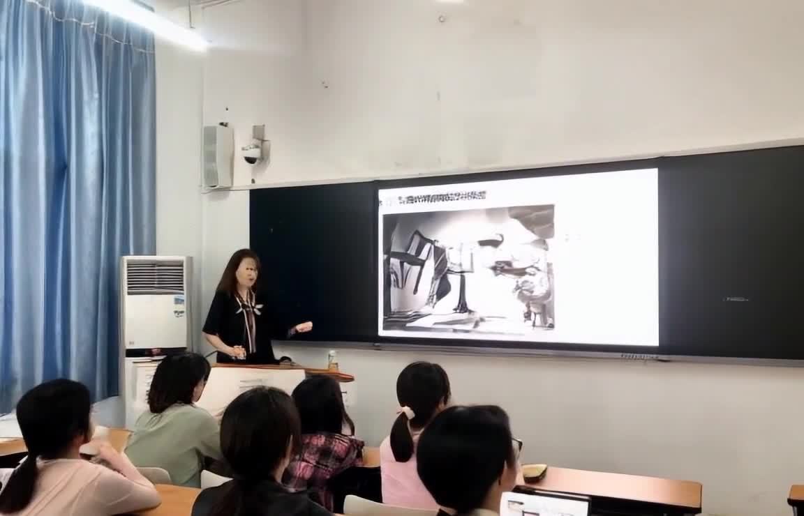 女老师课堂授课，学生听讲，黑板有图像。