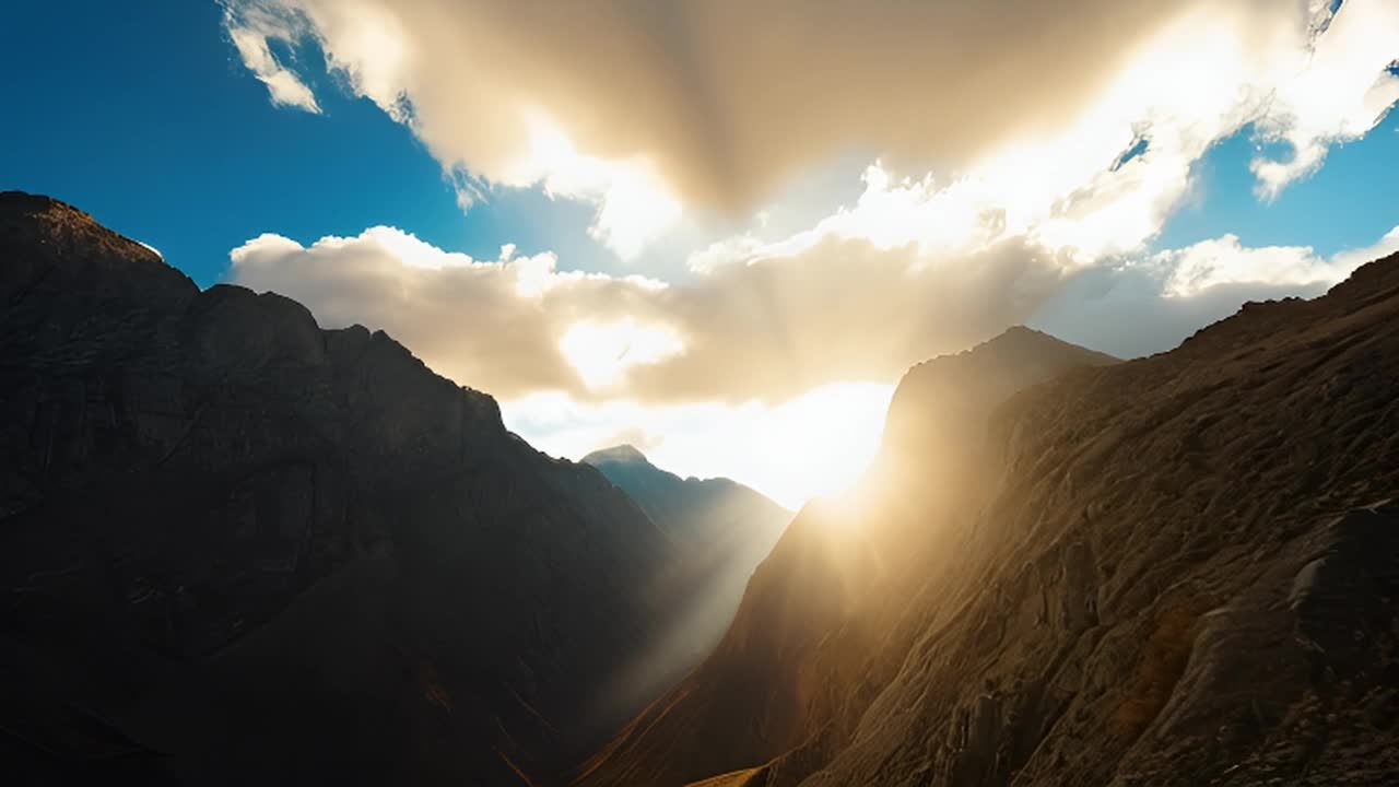 山脉雄伟壮观，天空布满了翻滚的云朵。太阳从低角度照
