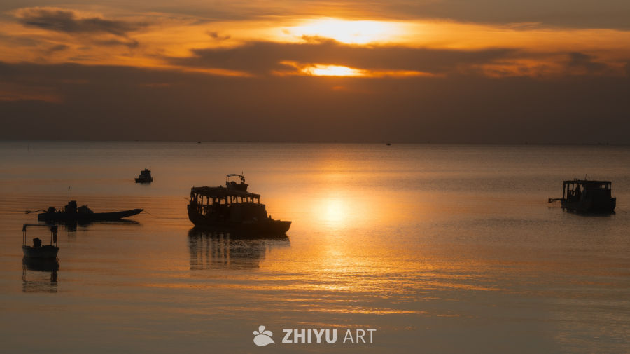 金色日落下的渔船剪影