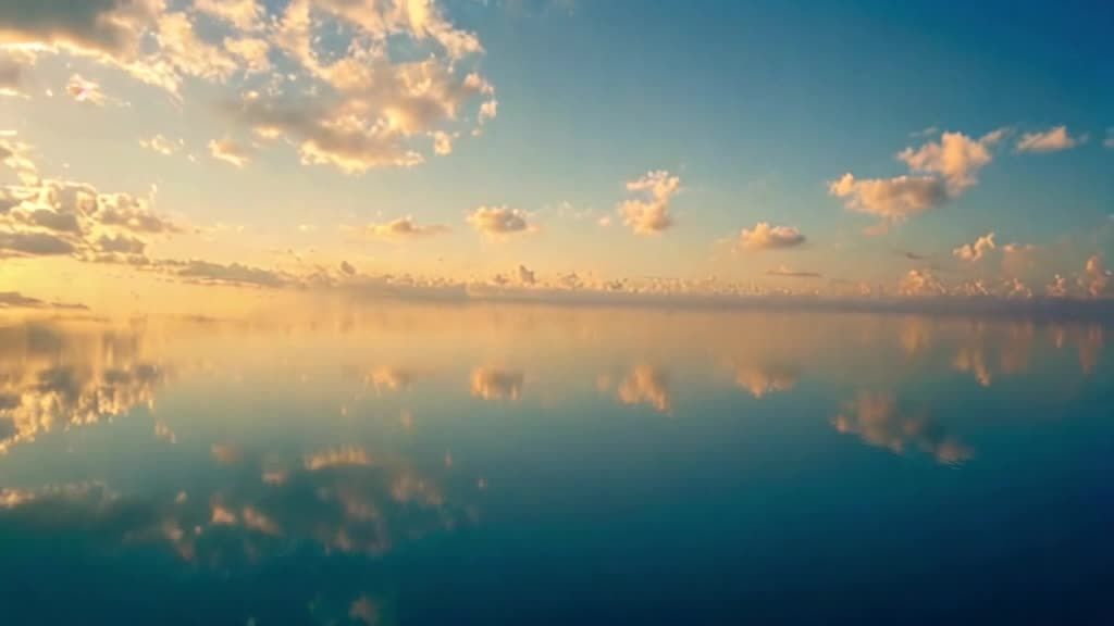 图片展示了一片宁静的海面，海面上倒映着蓝天白云。天
