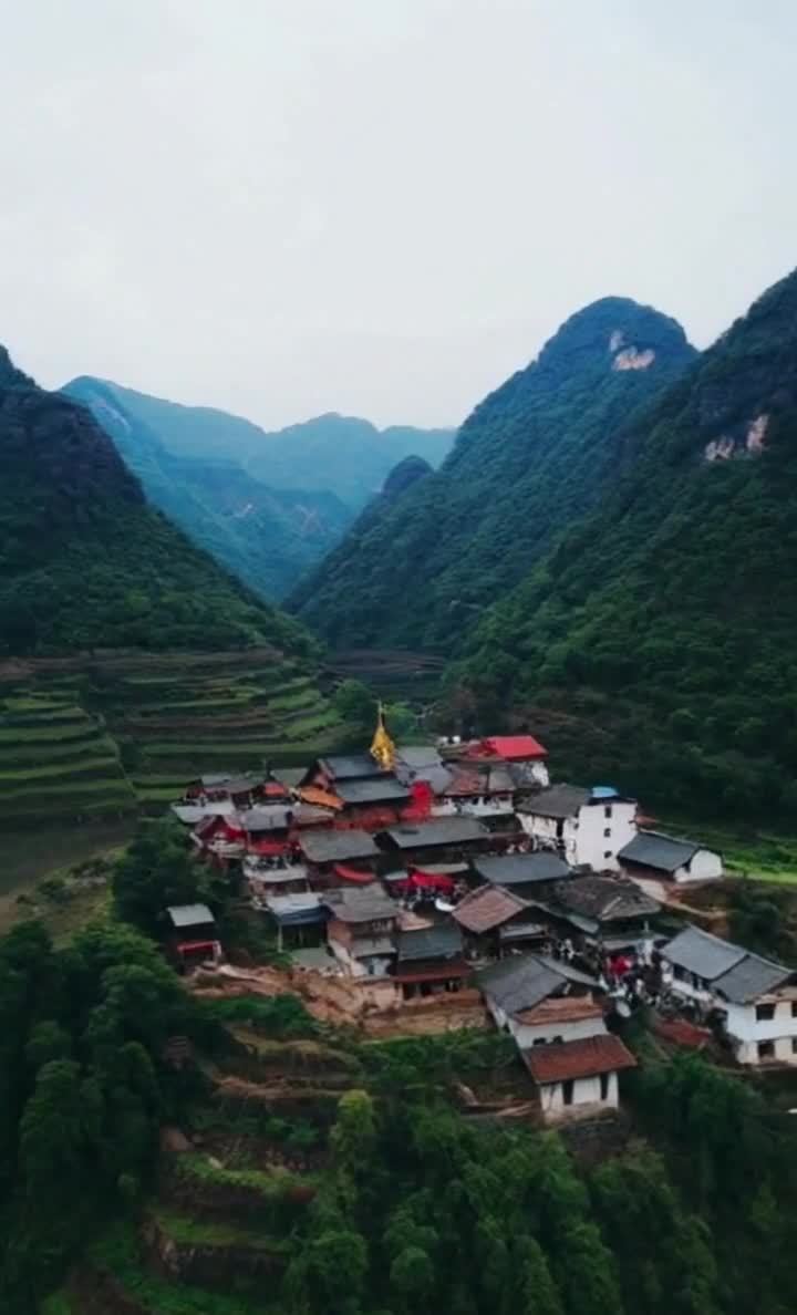 峡谷中的村庄，梯田环绕，山峰耸立。