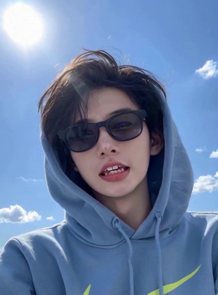 蓝天白云下戴太阳镜的运动帽衫青年