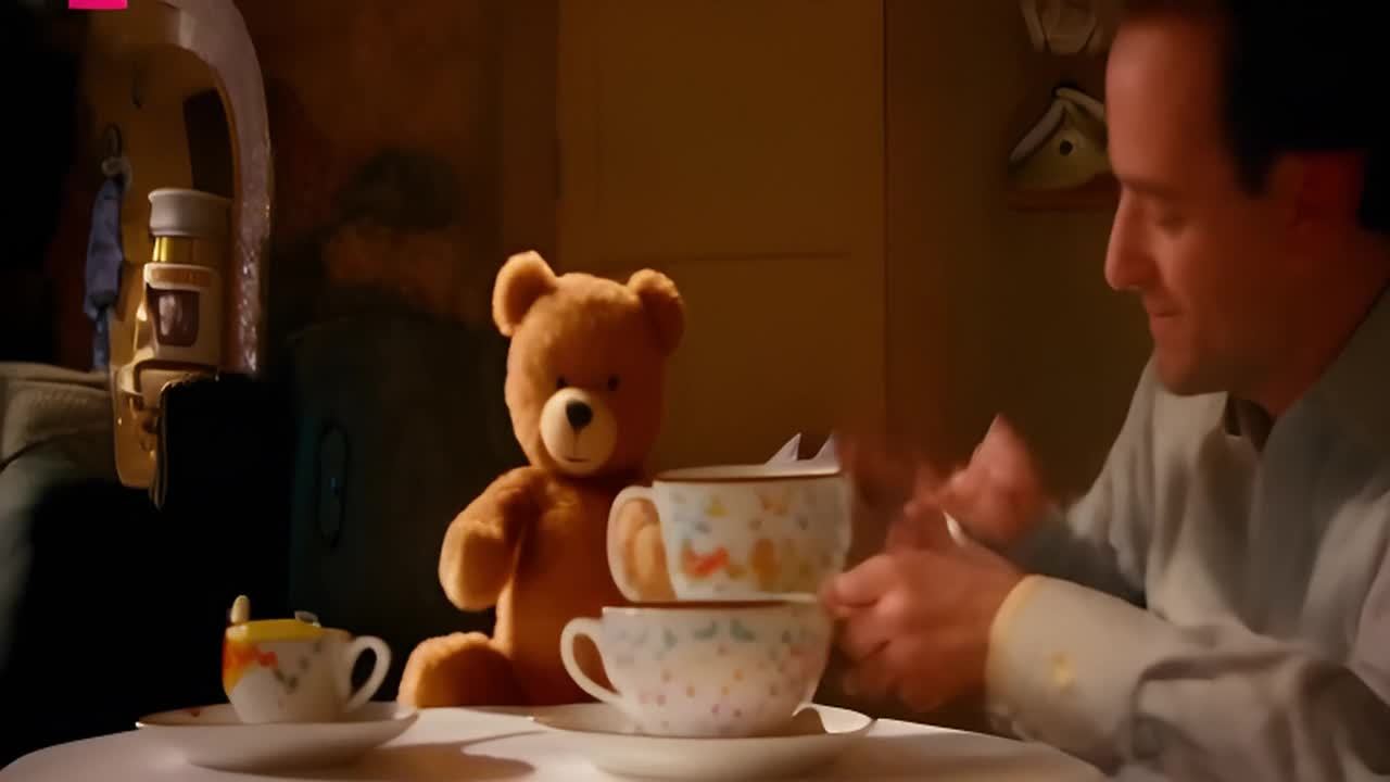 一个人正在和一只泰迪熊参加茶话会，桌子上有三只茶杯