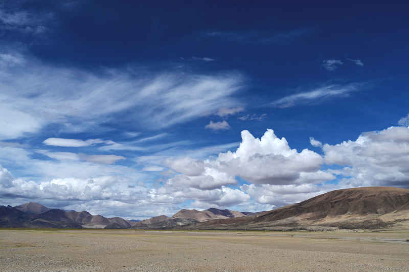 西藏阿里地区蓝天白云下广袤的草原和山脉