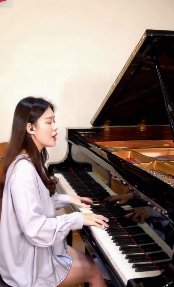 女子戴耳机弹奏黑色钢琴并唱歌