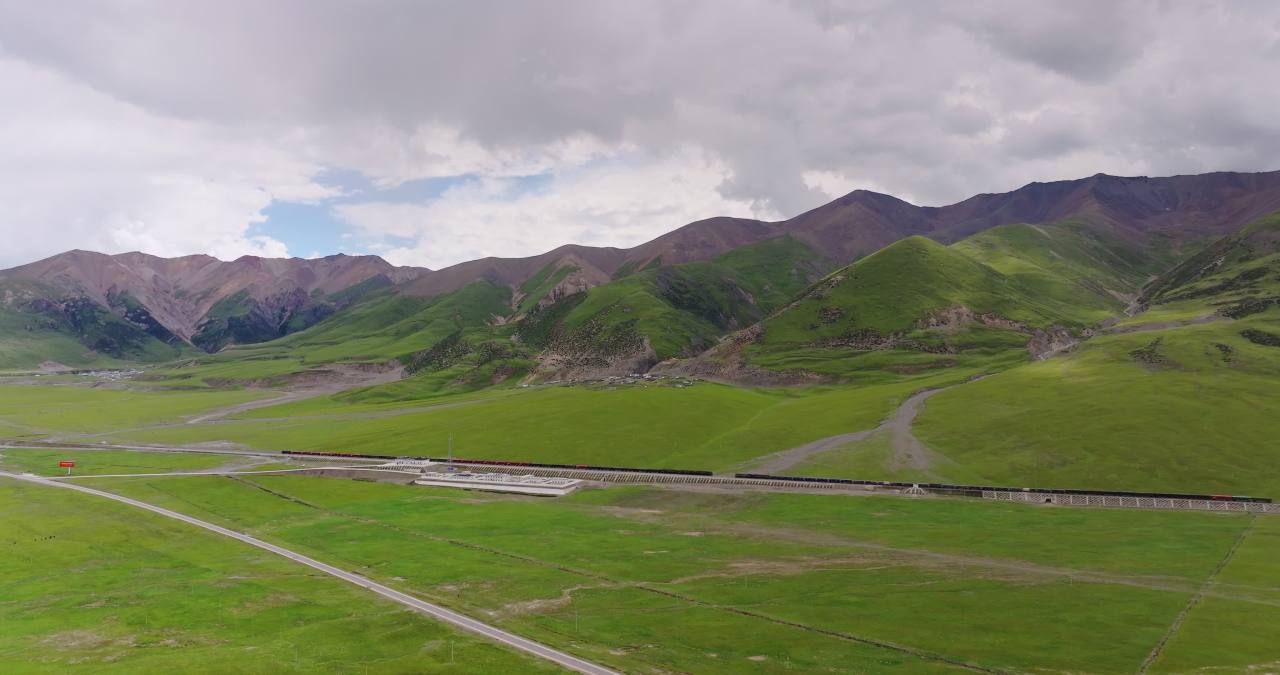 西藏那曲青藏高原雪山草原之间青藏铁路行驶的列车大气航拍