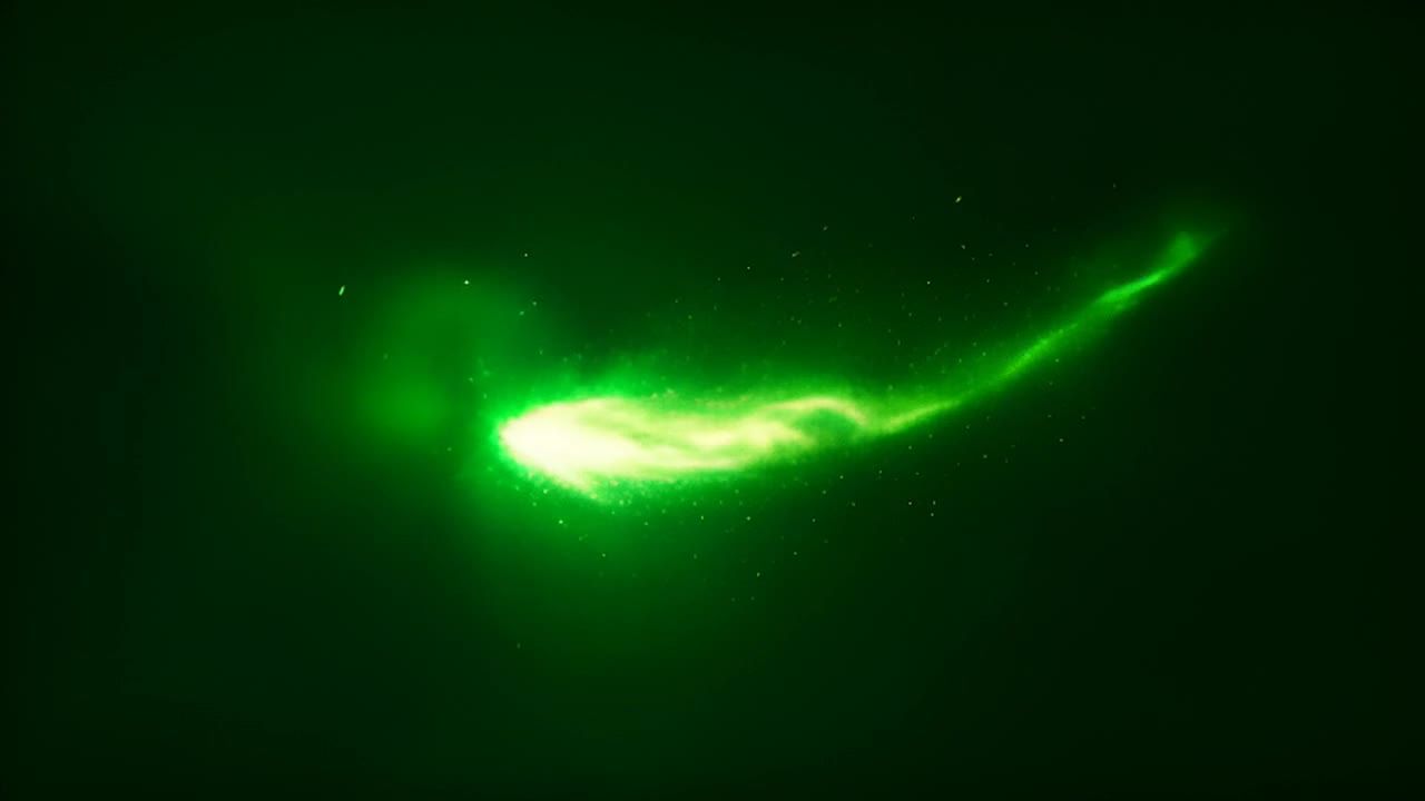 一个绿色的光点在深色背景中移动，拖着一条光尾，周围